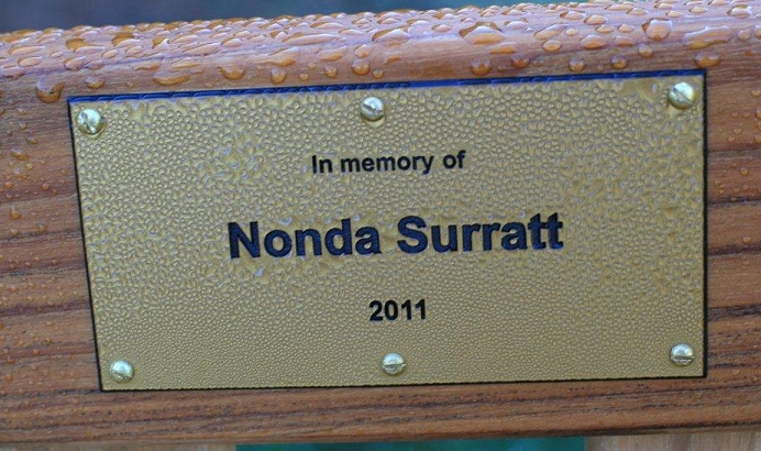 Memorial plaque attached to the center back rail of the bench